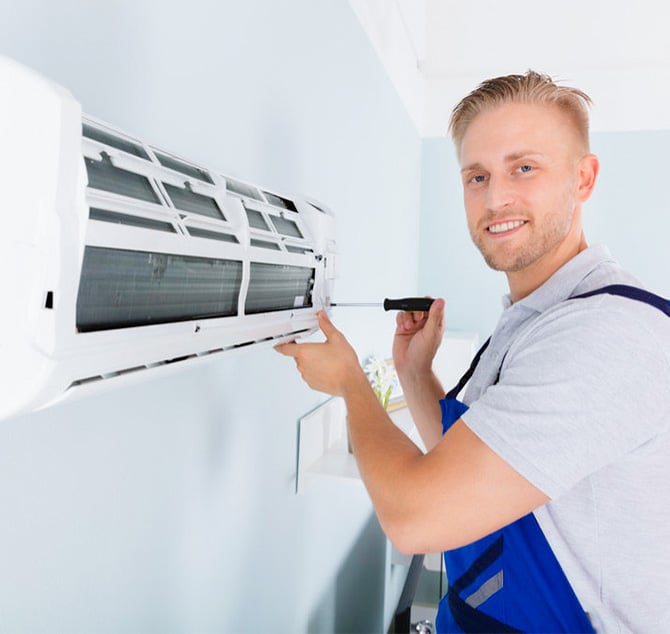 Handyman in blue overall fixing a inside air condition unit