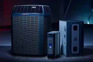 Three HVAC system units, including an outdoor condenser and two indoor components, on a grated floor.
