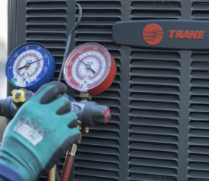 Gloved hand checks pressure gauges on a Trane HVAC unit.